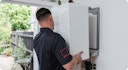 a male heating engineer in a black top installing a boiler