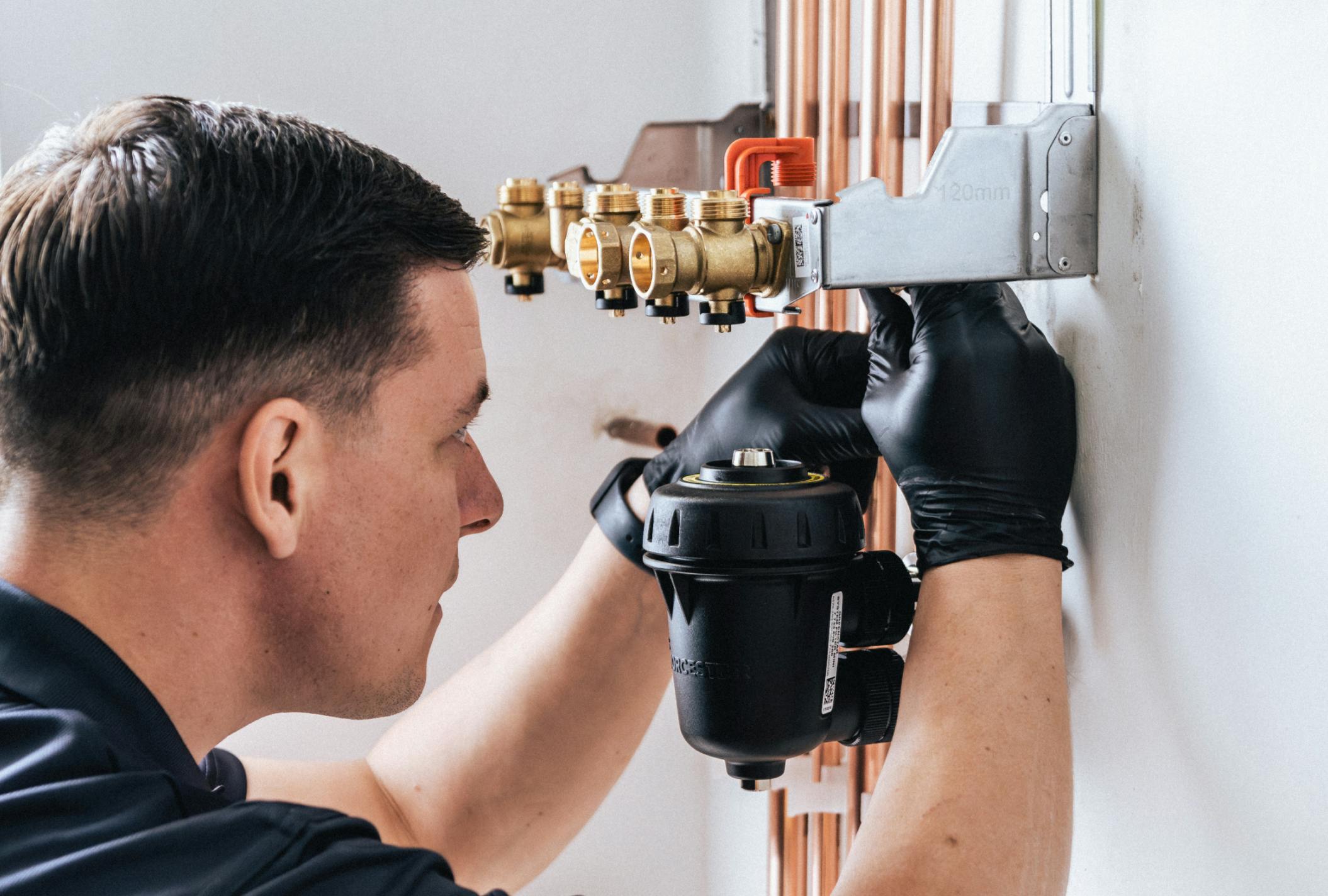 a BOXT engineer installing pipework and a magnetic boiler filter