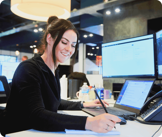 A female BOXT employee in BOXT offices smiling using a laptop 