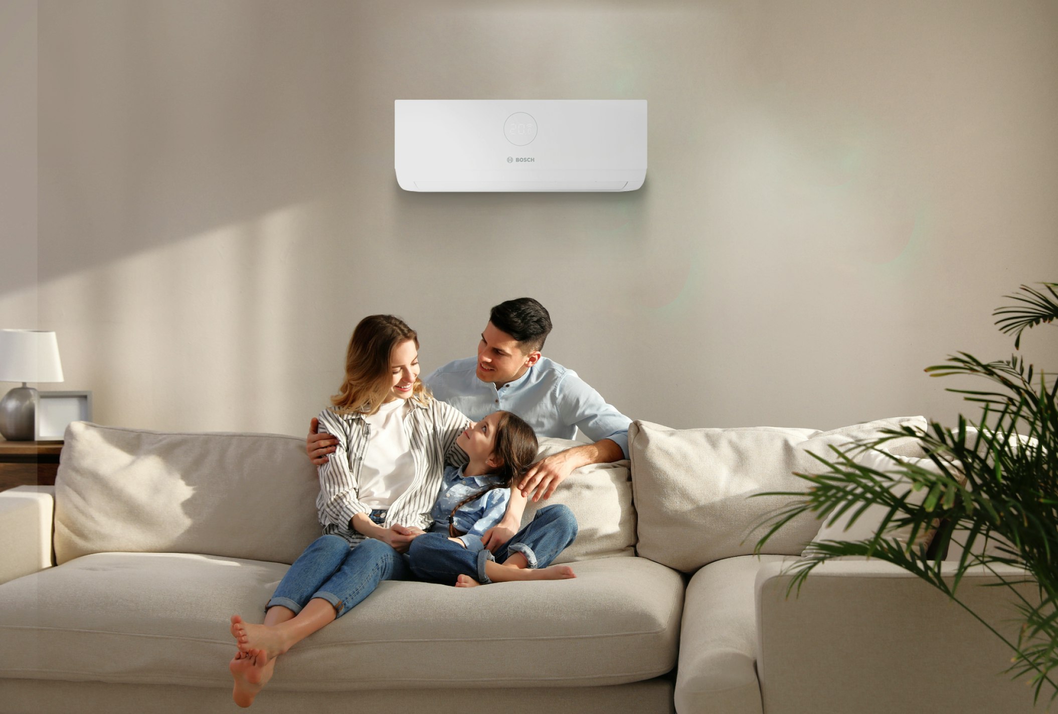 a family sitting on a sofa underneath an air conditioning unit