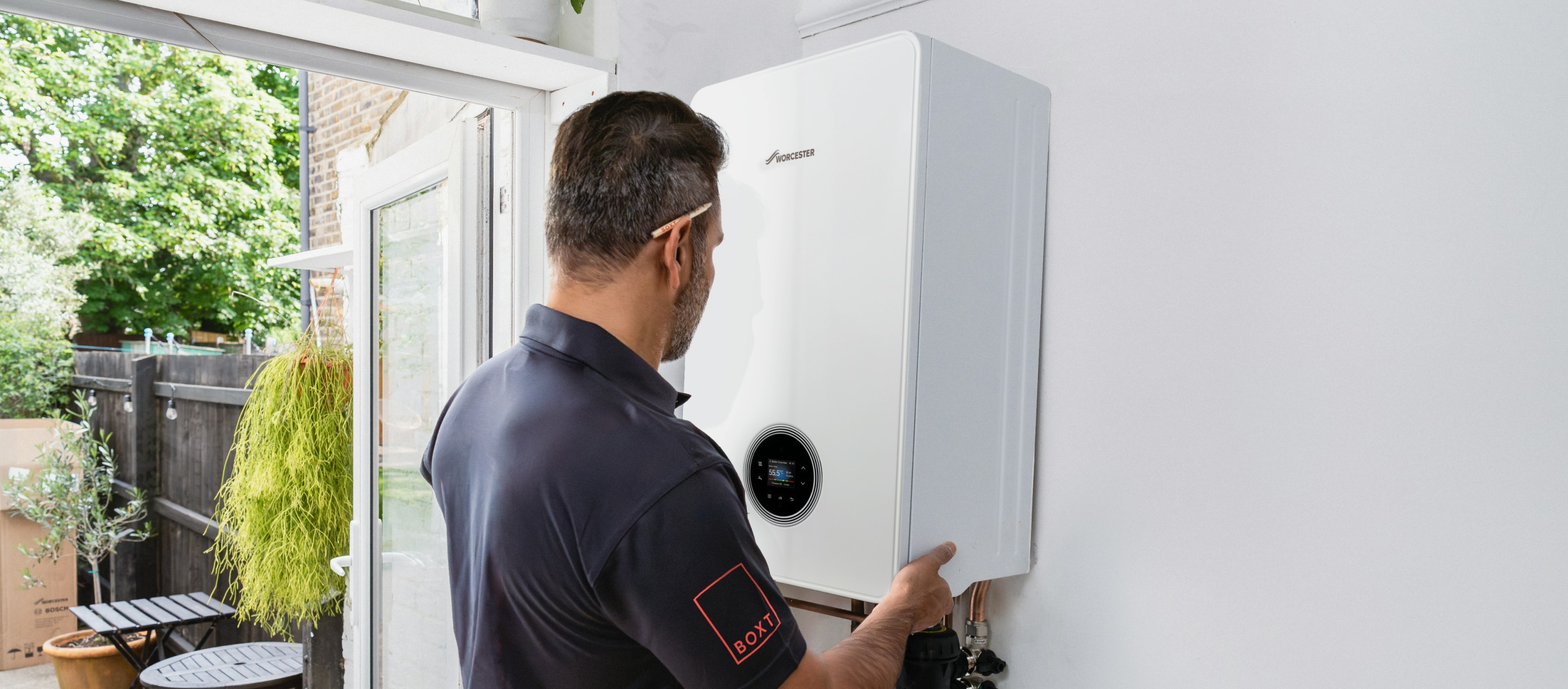 A BOXT engineer is fitting a boiler to the wall