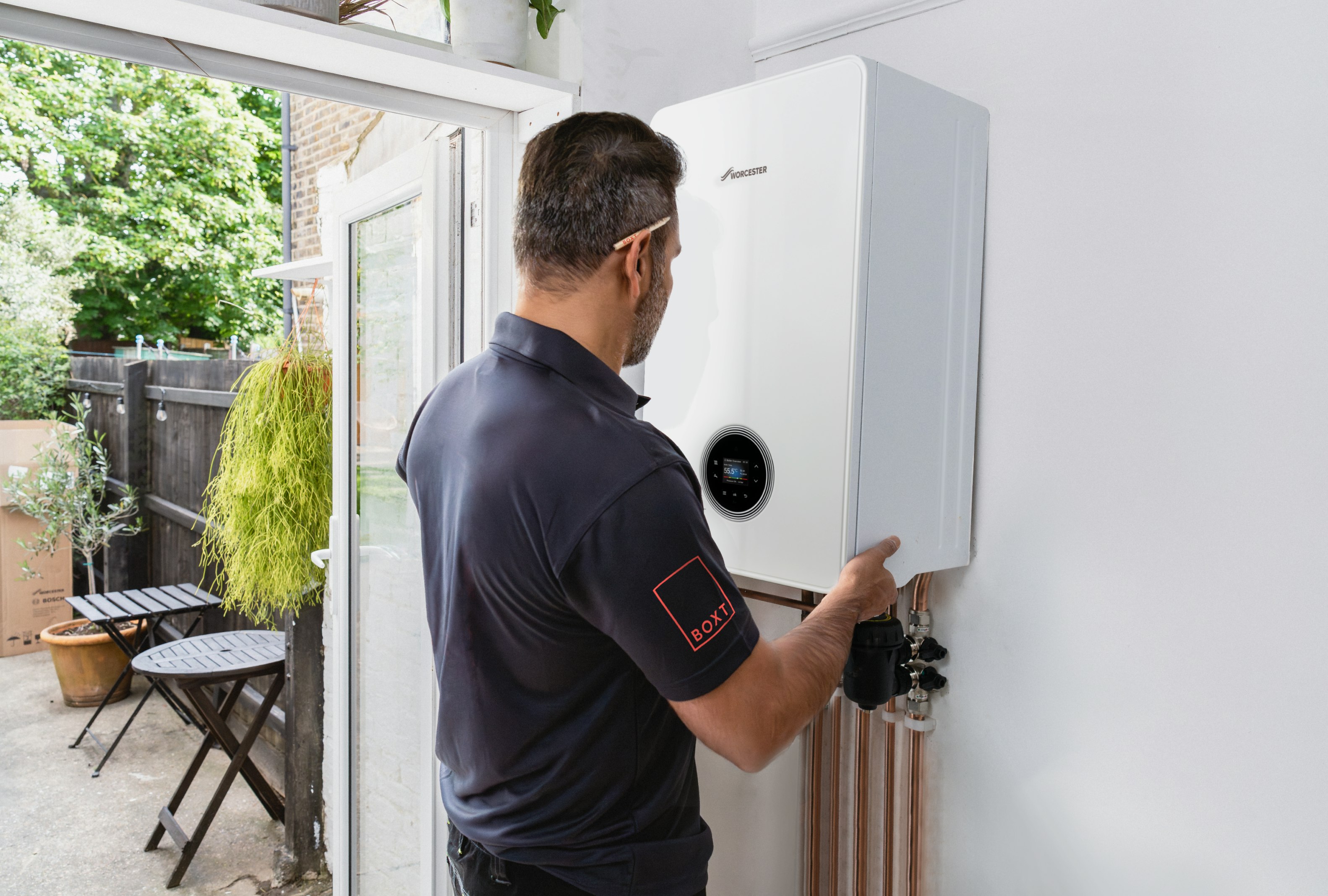 A BOXT engineer is fitting a boiler to the wall