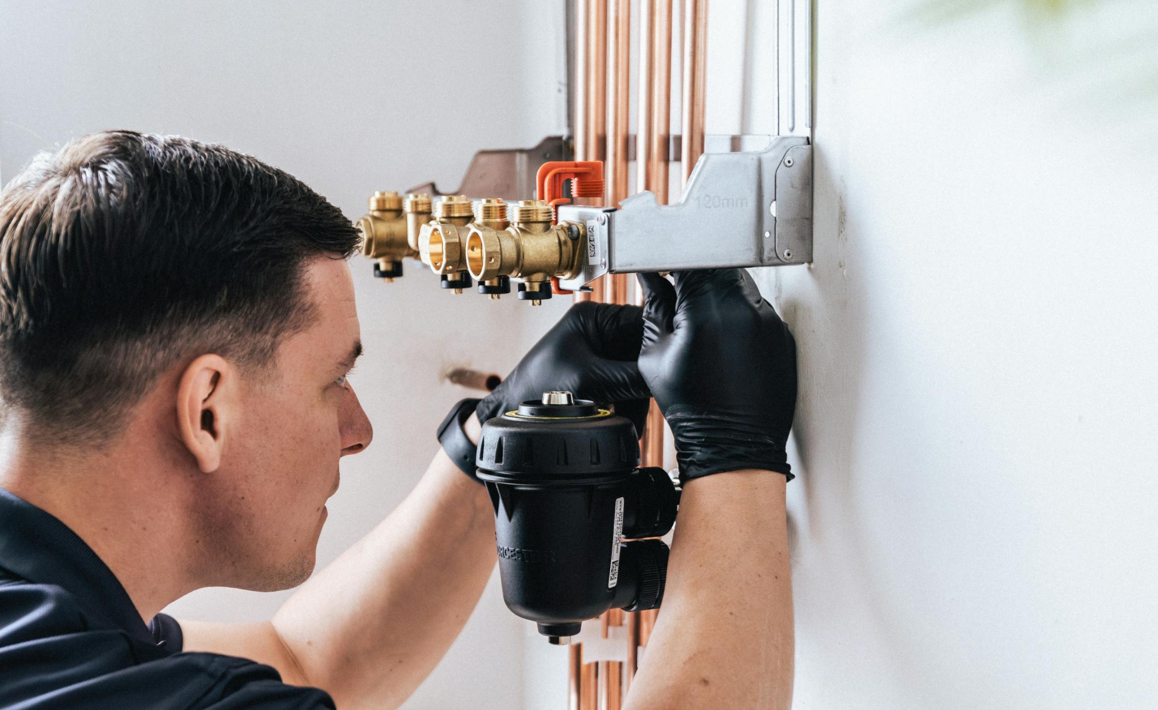 a BOXT engineer installing pipework and a magnetic boiler filter
