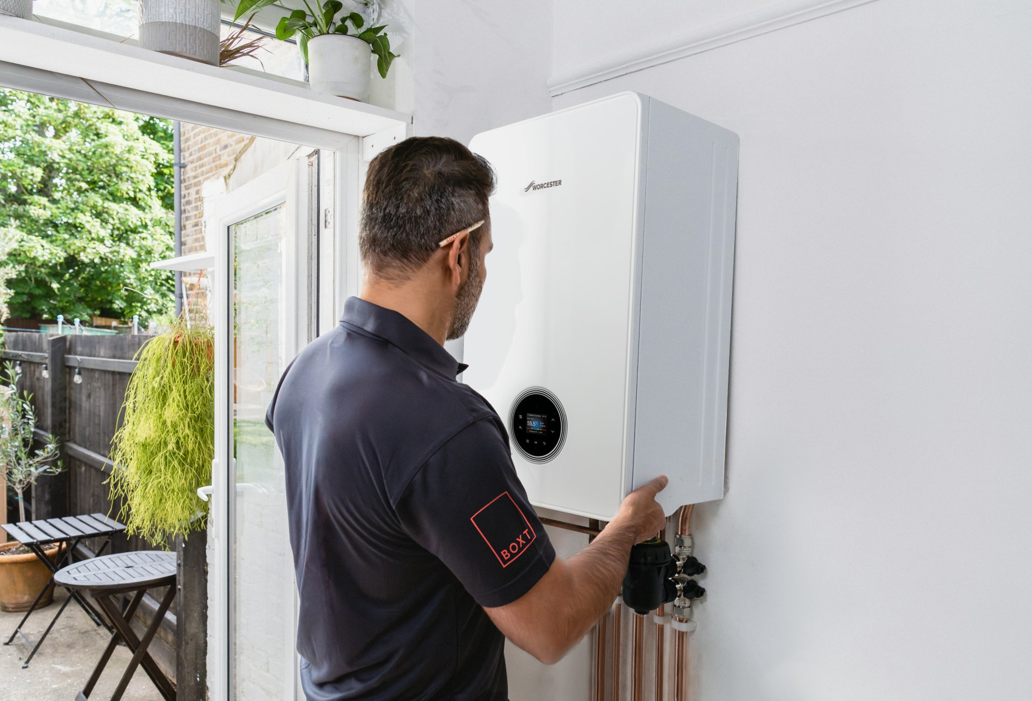 A BOXT engineer is fitting a boiler to the wall