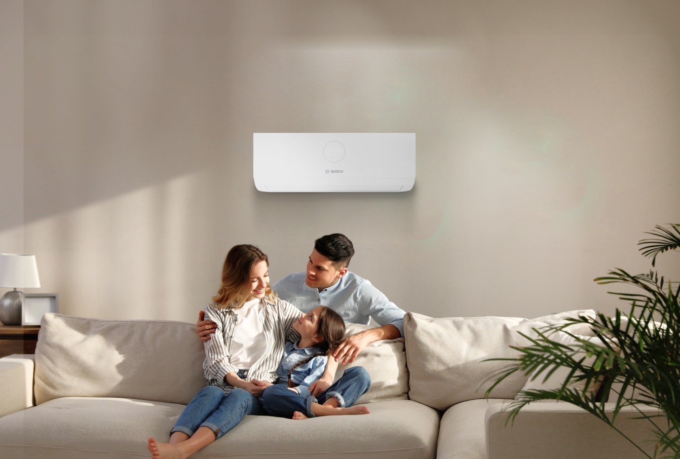 a family sitting on a sofa underneath an air conditioning unit